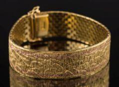 A two-colour 18ct gold bracelet:, of textured mesh linking, 17mm wide, 46gms gross weight.