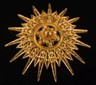 A gold star burst faceted and pierced pendant/brooch: 61mm diameter, 27.5gms gross weight.