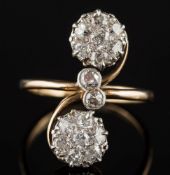 A diamond mounted cross-over ring: with two circular old-cut diamond-set clusters,