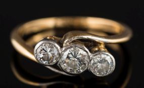 A gold and diamond three-stone cross-over ring: with circular brilliant-cut stones approximately 0.