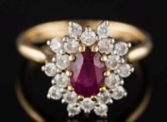An 18ct yellow gold, ruby and diamond oval cluster ring: the oval ruby 6.8mm long x 4.9mm wide x 3.