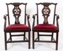 A pair of George III carved mahogany elbow chairs: in the Chippendale taste,