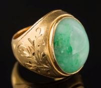 A gentleman's green jade single stone ring: the oval jade approximately 21mm long x 13mm wide x 9.