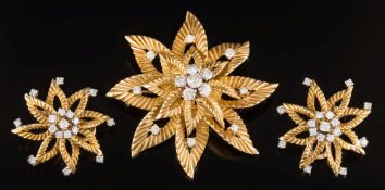 An 18ct gold and diamond mounted flower head brooch and matching ear-clips: each with a circular