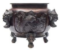 A Japanese bronze tripod jardiniere: decorated in relief with foliate shaped panels of birds in