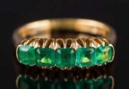 An 18ct gold and emerald five-stone ring: the central emerald approximately 3.7 mm wide x 4.