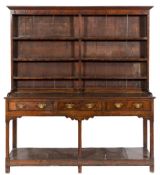 An 18th Century oak dresser:, the shelved superstructure with a moulded cornice and later pine back,