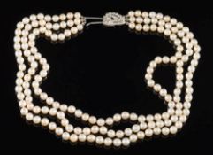 A graduated cultured pearl three-string necklace: with diamond mounted foliate cluster clasp.