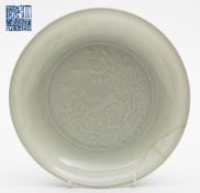 A Chinese porcelain white glazed shallow dish: the centre moulded in low relief with a circular