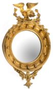 A 19th Century carved giltwood and gesso circular convex mirror: surmounted by a figure of an eagle