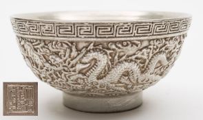 An unusual Chinese porcelain silver lustre bowl: the exterior moulded with three dragons pursuing
