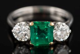 An emerald and diamond three-stone ring: the rectangular emerald approximately 7.1mm long x 6.
