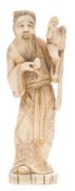 A Japanese carved ivory okimono of a bearded figure: standing and holding a cockerel in one hand