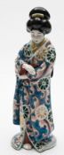An Arita porcelain figure: of a Geisha modelled standing in florally patterned robes, Meiji,