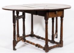 An 18th Century oak oval gateleg table:, with a hinged top on turned underframing,
