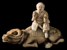 A Japanese carved and stained ivory okimono of a man seated on an ox,