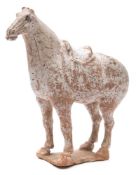 A Chinese terracotta figure of a horse: standing four square and wearing a saddle,