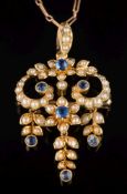 An Edwardian 15ct gold sapphire and seed pearl pendant: of open work scroll design suspending three