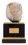 A carved limestone fragment of Rameses II: raised on a rectangular polished black marble and gilt