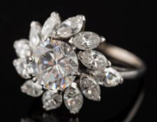 A diamond and gem-set circular cluster ring: with central diamond simulant claw-set within a