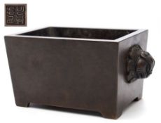 A Chinese bronze censer: of mildly tapering rectangular form with peg feet and two grotesque mask
