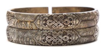 A pair of Chinese white metal bangles: each the exterior decorated in low relief with dragon,
