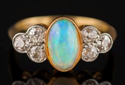An 18ct gold, opal and diamond seven stone ring: the central oval opal approximately 9.2mm long x 5.