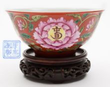 A Chinese porcelain famille rose ruby ground bowl: of circular form with mildly flaring rim,