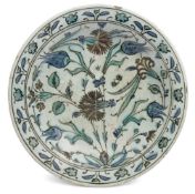 An Iznik pottery dish: of circular form the centre painted with tulips, carnations,