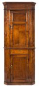 An 18th Century oak standing corner cupboard:, with a moulded cornice and canted angles,