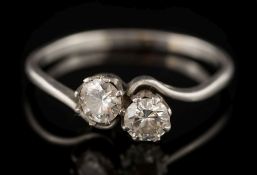 A platinum and diamond two-stone crossover ring: with circular brilliant-cut diamonds,