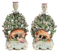 A pair of Derby porcelain fox and hen candlesticks: modelled with a seated fox devouring a hapless