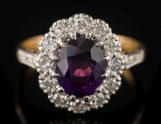 An 18ct gold, amethyst and diamond oval cluster ring: the central oval amethyst 9mm long x 7.