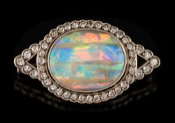 A black opal and diamond mounted oval brooch: the central oval black opal 19mm x 15mm,
