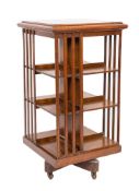 An Edwardian oak square revolving bookcase:, with a moulded top and slatted uprights,
