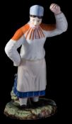Two Gardner (Moscow) porcelain figures of Peasant Dancers: he wearing a coat and mittens in dancing
