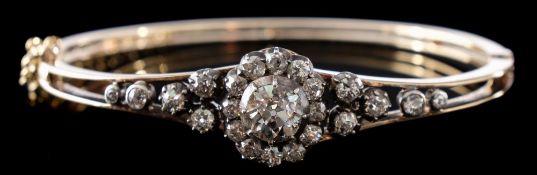 A late 19th century gold, silver and diamond mounted hinged bangle: with central oval cluster,