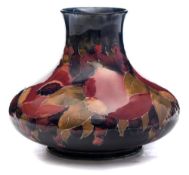A Moorcroft pottery vase: of squat form tube lined in the Pomegranate pattern in red,