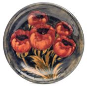 A Moorcroft pottery dish: tubelined in red yellow and green in the Poppy pattern,
