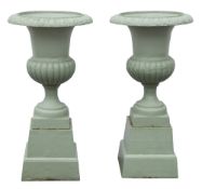 A pair of painted cast iron garden urns of campagna shape:, on square tapered plinths,
