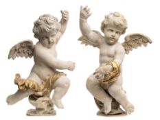 A pair of carved wood and decorated figures of cherubs: each with one arm raised and outstretched