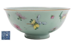 A Chinese porcelain bowl: the celadon glazed exterior enamelled in the famille rose palette with