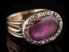 An antique gold, ruby and diamond oval cluster ring: with central oval ruby 13.4mm long x 9.