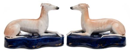A pair of Staffordshire pottery quill stands: each modelled in the form of recumbent greyhounds on