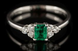 An emerald and diamond seven-stone ring: the central rectangular emerald approximately 0.