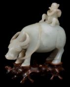 A Chinese pale celadon jade carving of a boy on a water buffalo: the boy playing a flute,