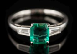 An emerald and diamond ring: the rectangular-cut emerald estimated to weigh 0.