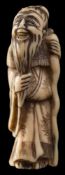 Two Japanese ivory netsuke: the first of a Chinese sage wearing a wide brimmed hat and robes,
