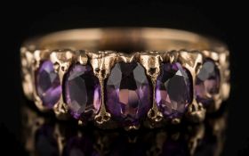 An amethyst five-stone ring: with graduated, oval amethysts in scroll work setting,