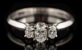A diamond three-stone ring: the central oval-cut diamond 5.5mm long x 3.